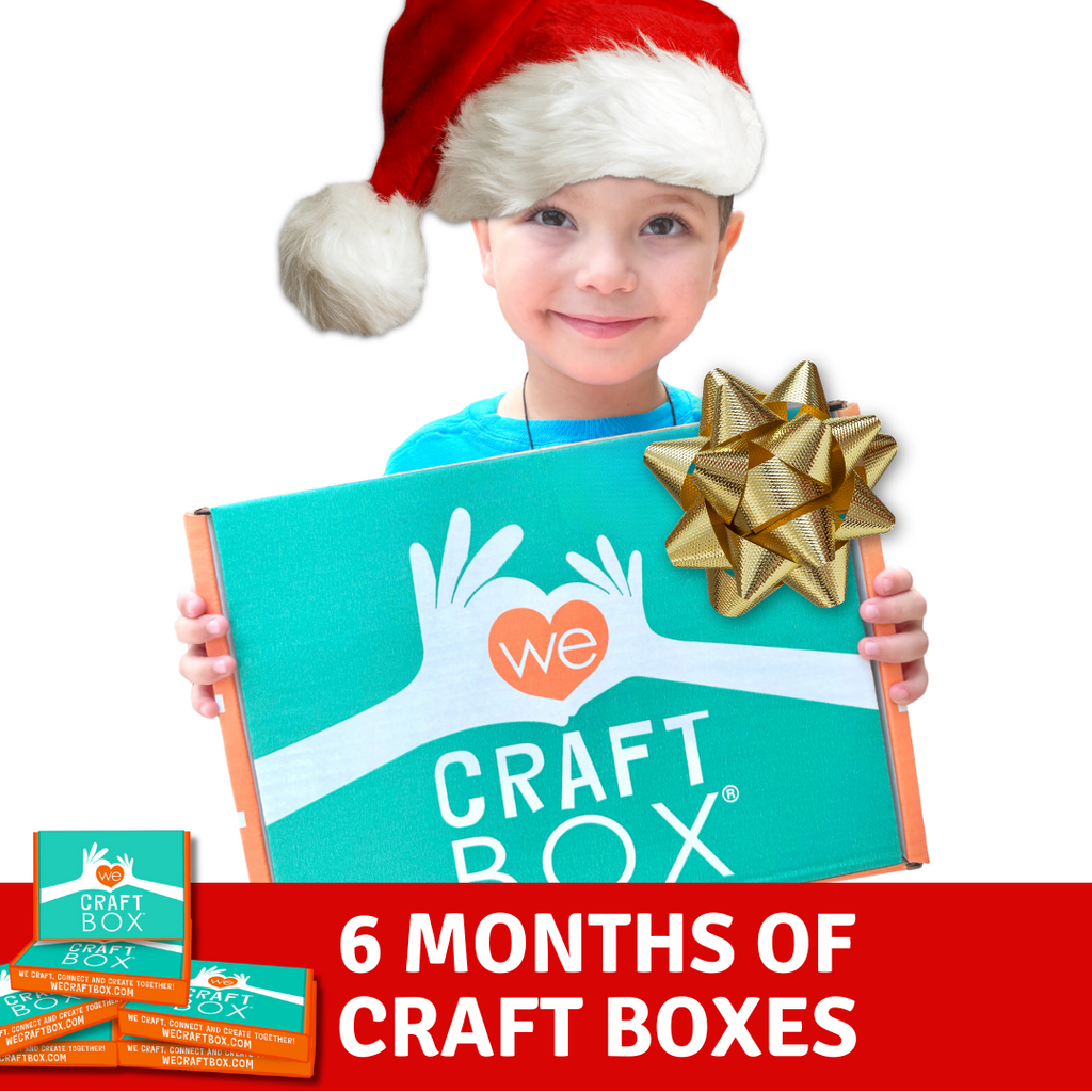 A child holding a Craft Box gift package with a Santa hat on, indicating a festive craft kit for Christmas.